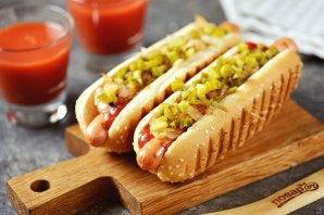 Хот-дог с жареным луком и солёными огурцами на сковороде Хот-дог с жареным луком и солёными огурцами на сковороде