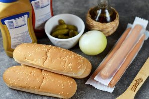 Хот-дог с жареным луком и солёными огурцами на сковороде Хот-дог с жареным луком и солёными огурцами на сковороде