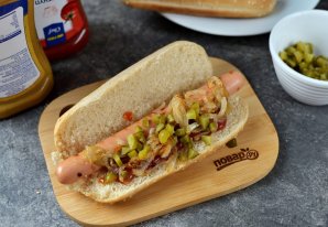 Хот-дог с жареным луком и солёными огурцами на сковороде Хот-дог с жареным луком и солёными огурцами на сковороде