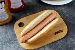 Хот-дог с жареным луком и солёными огурцами на сковороде Хот-дог с жареным луком и солёными огурцами на сковороде